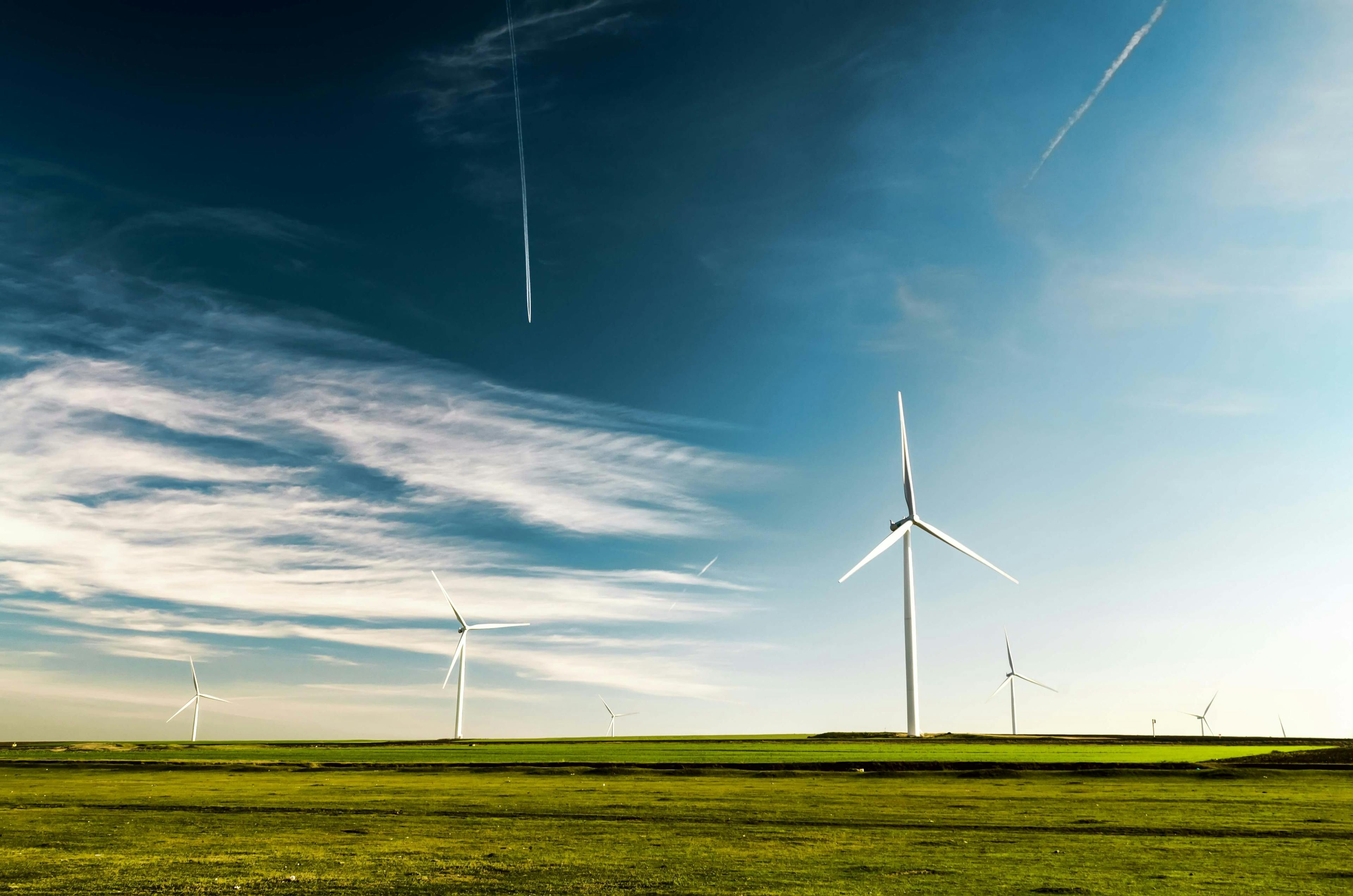 Wind turbines in a field. Vivid green grass with a blue sky backdrop